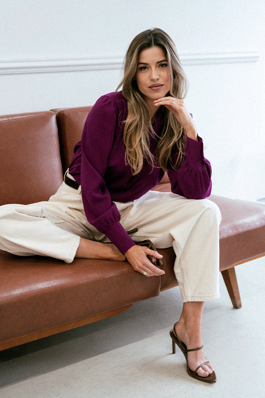 Kobieta w eleganckiej koszuli siedząca na sofie podczas sesji fotograficznej​